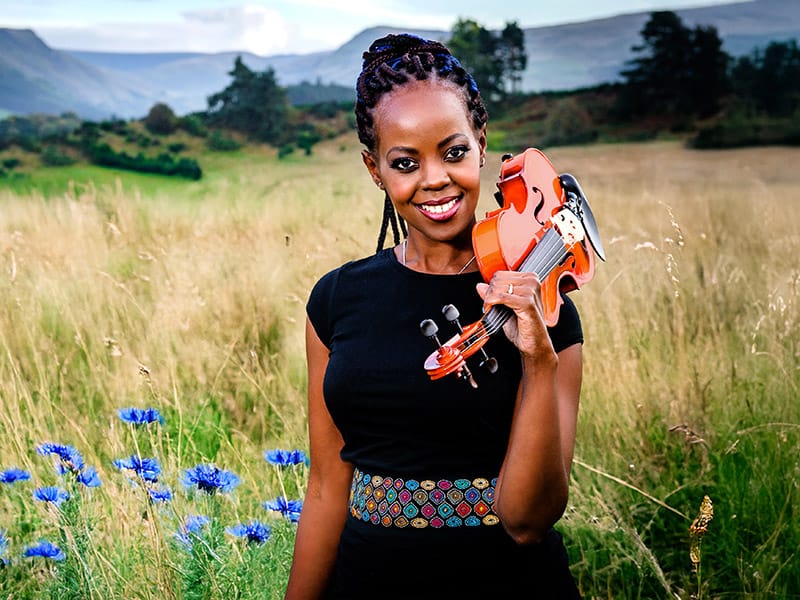 promo photo of female musician holding violin in scenic location by commercial photographer in Perthshire